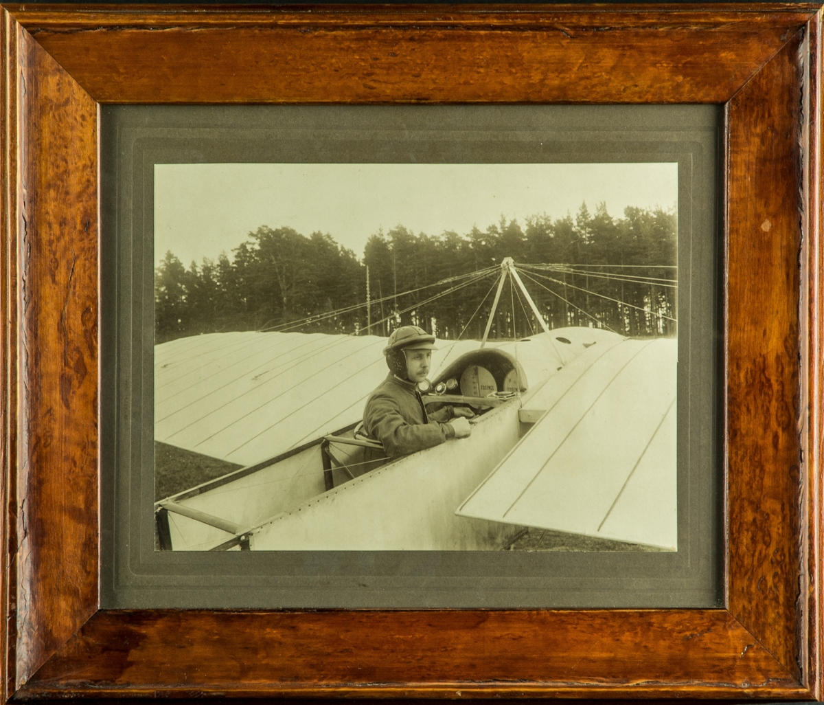 Porträtt. Löjtnant Carl Silow sitter i flygplan Blériot XI vid Carl Cederströms flygskola på Malmen, 1912. Inramat foto.