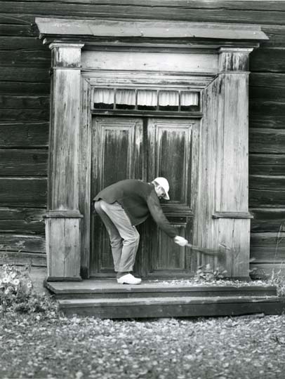 En man sopar trappan vid Kämpens hembygdsgård.