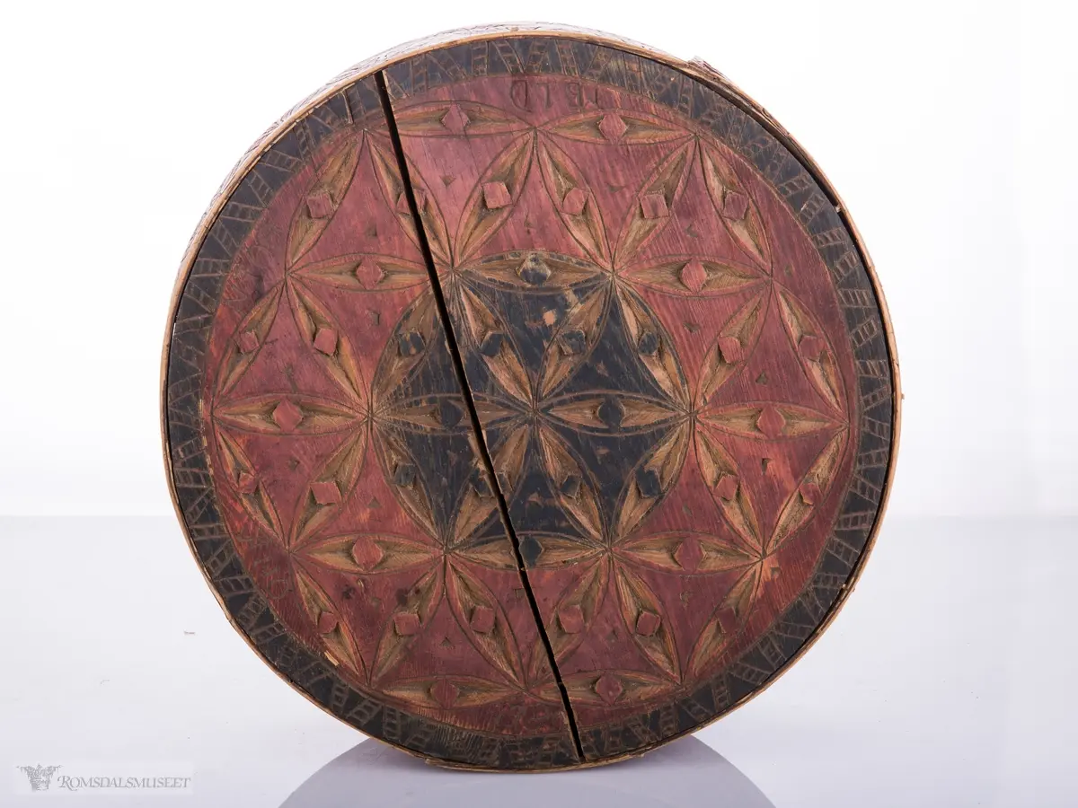 Eit slag seksbladrosemønster på lokk. Bueformede skaverte border på trosken.