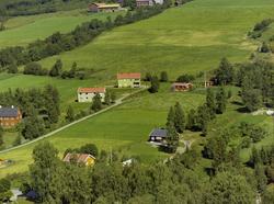 Flere eneboliger. Kulturlandskap. Gårdsbruk i bakgrunnen.
