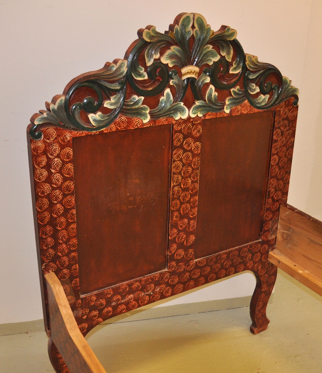 Seng med to sengegavler og to sidevanger. Den ene sidevangen er skåret ned på et lavere nivå. Ryggavlen er høyere enn fotgavlen. De har begge to fyllinger og krone prydet med akantusskurd. Fotgavlens fyllinger har skårne akantusrosetter på utsiden. Svungne bein. Treskurden er polykrom, mens senga er malt lys elgfenbeinsfarget med brun maling over, der en form for stempel har vært brukt for å fjerne deler av overmalingen, slik at et konglelignende mønster framtrer.