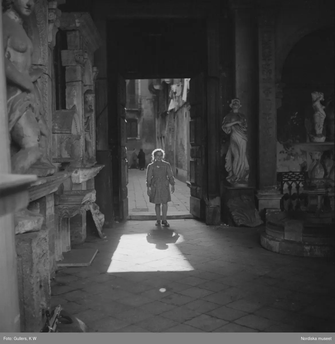 En liten flicka står i dörren och tittar på  marmorstatyerna i kardinal Grimanis palats i Venedig, Italien. Palazzo Grimani.