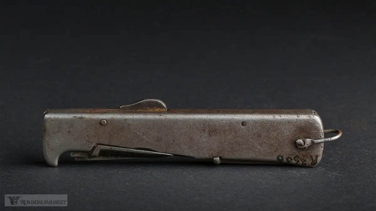 Foldbar tyskprodusert lommekniv. Kniven har to rom, et for hovedknivbladet, og et for en syl og en boksåpner. En liten hempe i metall er naglet fast i bakkant av kniven.