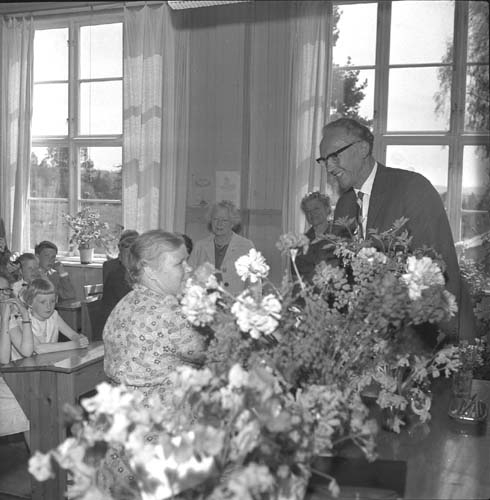 Sista skoldagen i Reaby skola 1962. Städerskan Edit Svahn avtackas med blommor. I bakgrunden står lärarinnorna Ruth Pettersson och Anna-Lisa Lundin.