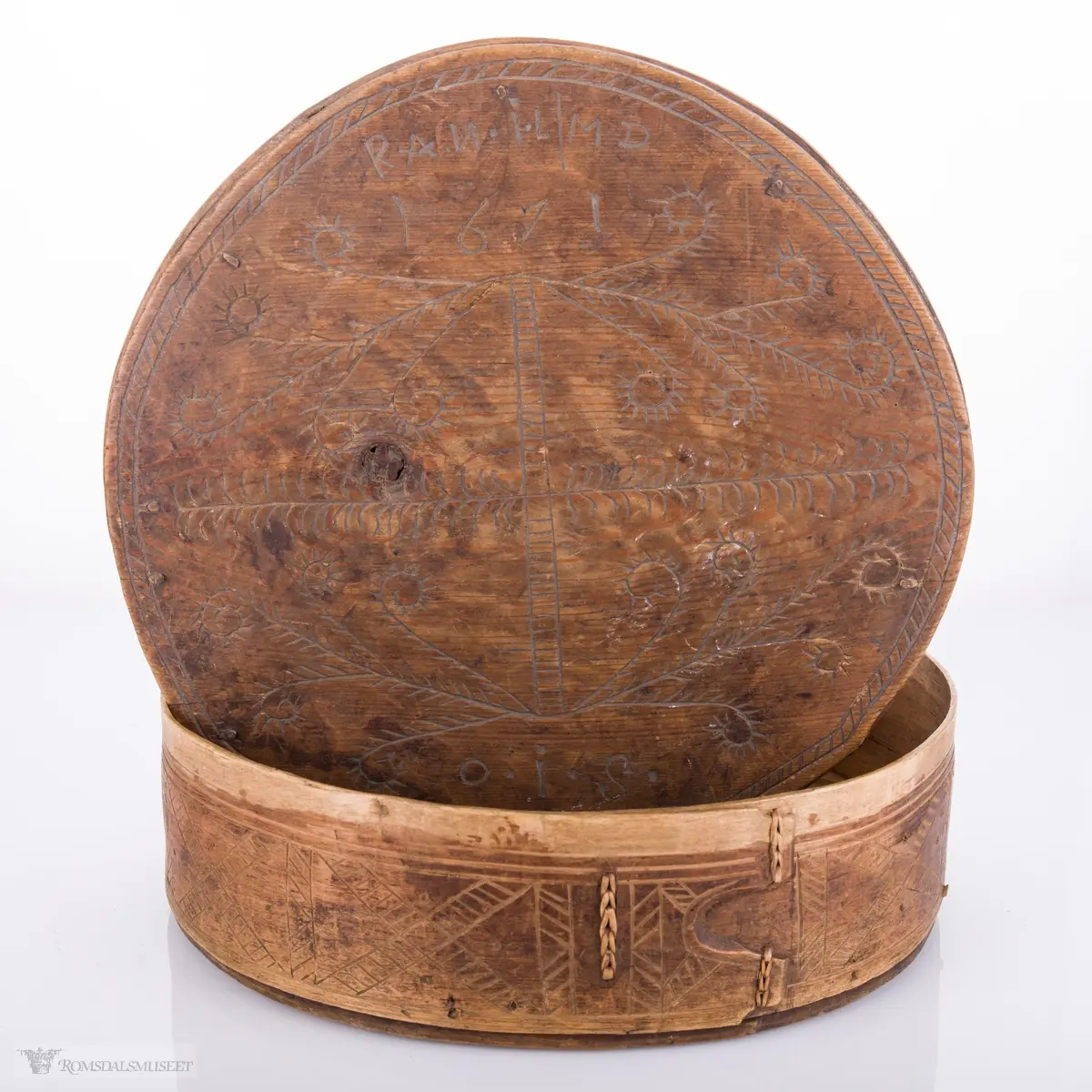 Eit kvistmønster/bregner på lokk. Skravert kryss- mønster langs trosken. Rosett av spetter i bunnen.