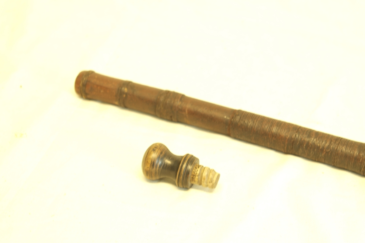 Spaserstokk (a) med håndtak/tapp (b). Laget i tre, never og jern. 
A) Hul trestokk surret med never. Nederst en jernskoning (beslag) som ender i en pigg. Øverst innvendige gjenger. 
B) Tapp i åpningen. Dreiet med gjenger.