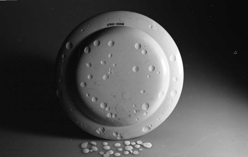 Baksida av en hvit tallerken, med flere skår som har falt av.