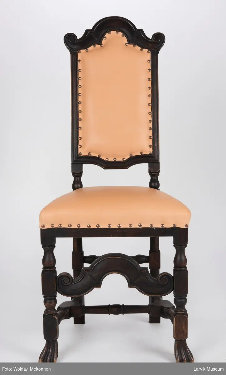 Høyrygget stol uten armlener med skinntrekk på sete og rygg.
