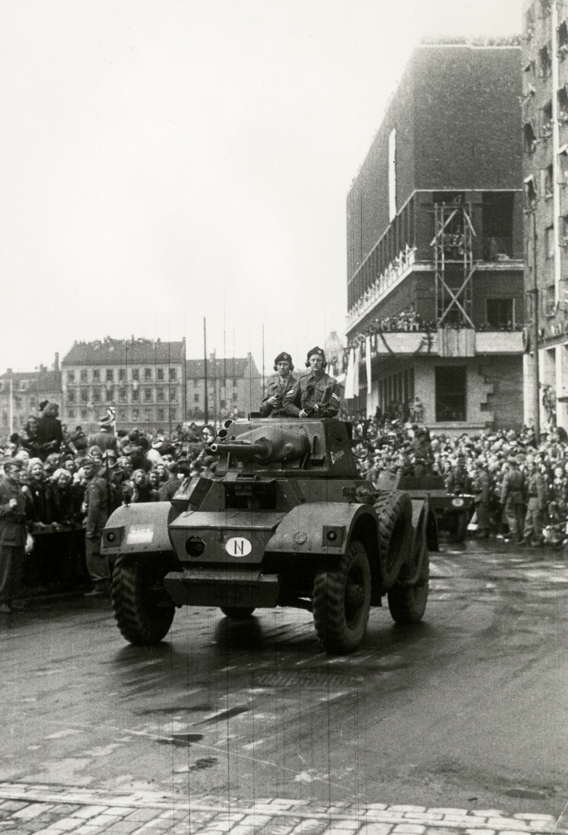 Fra Oslo under fredsdagene i 1945. Et militært kjøretøy har akkurat passert Rådhuset. Publikum i bakgrunnen.