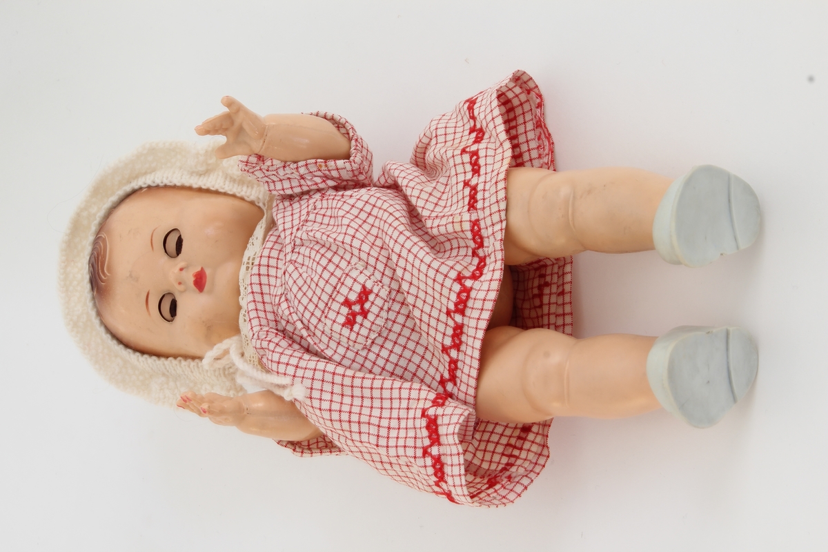 Siste eier Elisabeth Marthinsen. Gitt etter ønske fra Elisabeth til Kvinnemuseet etter hennes bortgang. Giver: datter, Heidi Graff.

Dukken er en dukke av merke "rosebud". Elisabeth hadde lette etter denne dukken i årevis. Det er ikke oppført hvor hun til slutt fant dukken eller hvor den er kjøpt. Dukken er liten, med øyne som "blunker/sover". Den har på seg en rutete kjole i rødt og hvitt, en hvit lue og grå sko. 

Da Elisabeth var 13 år og bodde i Bodø, ble hun tatt med "på ferie" til Oslo. Mor, far, bror, søster og Elisabeth reiste fra hjemmet. Elisabeth tok ikke med noen leker og fikk ikke sagt farvel til noen – verken familie eller venner. Hun fikk senere vite at " på ferie" betydde at de hadde flyttet. 

Som voksen ble det viktig for henne å få tilbake de dukkene hun hadde hatt som barn. Dette utviklet seg til å bli en hobby. Hun reiste rundt med ei venninne på markeder, antikkmesser og auksjoner for å bygge opp sin dukkesamling. Dette koste Elisabeth seg veldig med.  

Elisabeth flyttet til Kongsvinger i 1973, siden foreldrene hennes hadde flyttet hit. Hun var først husmor. Pendlet noen år til Oslo, og arbeidet så videre noen år i Kongsvinger.
