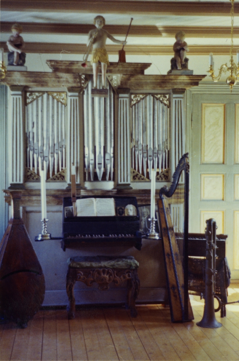 Bilde av Vollanorglet i orgelrommet. Det står en cecilium og en harpe ved siden av orgelet.