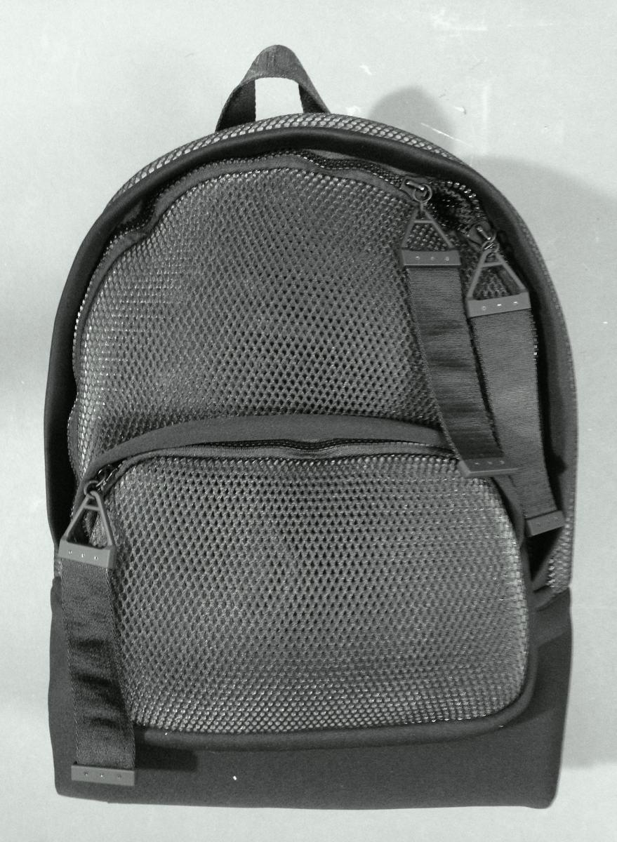 Liten sekk for trening. Sydd av nettstoff, der det ytre stoffet er laminert med flere lag nettstoff, og kjernen antagelig selvlysende, dvs av lysegrå refleksfibre. Sekken består av ett hovedrom og et lite ytterrom. Nedre del av både sekk og ytterrom er av tett neopren. Selve bunnen har en påsydd plate av gummi, med 4 "ben" i form av logoen "AW".  Innvendig bunnplate er imidlertid både bredere og lengre og av ukjente materiale. Sekken er flat nederst og buet i overkant, hovedrommet åpnes nesten helt ned i begge sider og lukkes med grov plastglidelås. Ytterommet åpnes i overkant og lukkes med tilsvarende glidelås. Innvendig er rommene fôret med et ekstra lag, enkelt nettstoff, og hovedrommet utstyrt med en ekstra lomme. Selene er regulerbare med spenner, er polstret, av neopren og utvendig forsterket med påsydde bånd av bevernylonlignende materiale ivevd "WANG" gjentatte ganger. Tilsvarende stropp øverst, til bæring i hånden. Under selefestene en ekstra lomme, lukket med samme grove glidelåstype. Nedi lommen ligger et påsydd regntrekk av tynt, vannavstøtende matriale, med påtrykt "AW" i et sammenhengende mønster utført i lysreflekterende trykkfarge over det hele. Med påsydd elastikk langs ytterkanten, kan trekket raskt tas ut og vikles omkring sekkens front og holde seg på plass i regnvær. Alle glidelåser er utstyrt med en "drastropp" av det sorte bondet ivevd WANG.