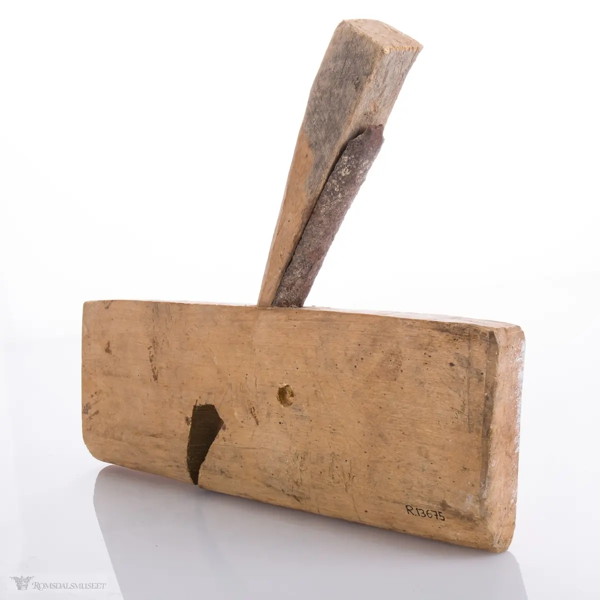 Enkel høvel skåret ut av et stykke tre som er avrundet under. Langt avrundet jern og utskåret kile.