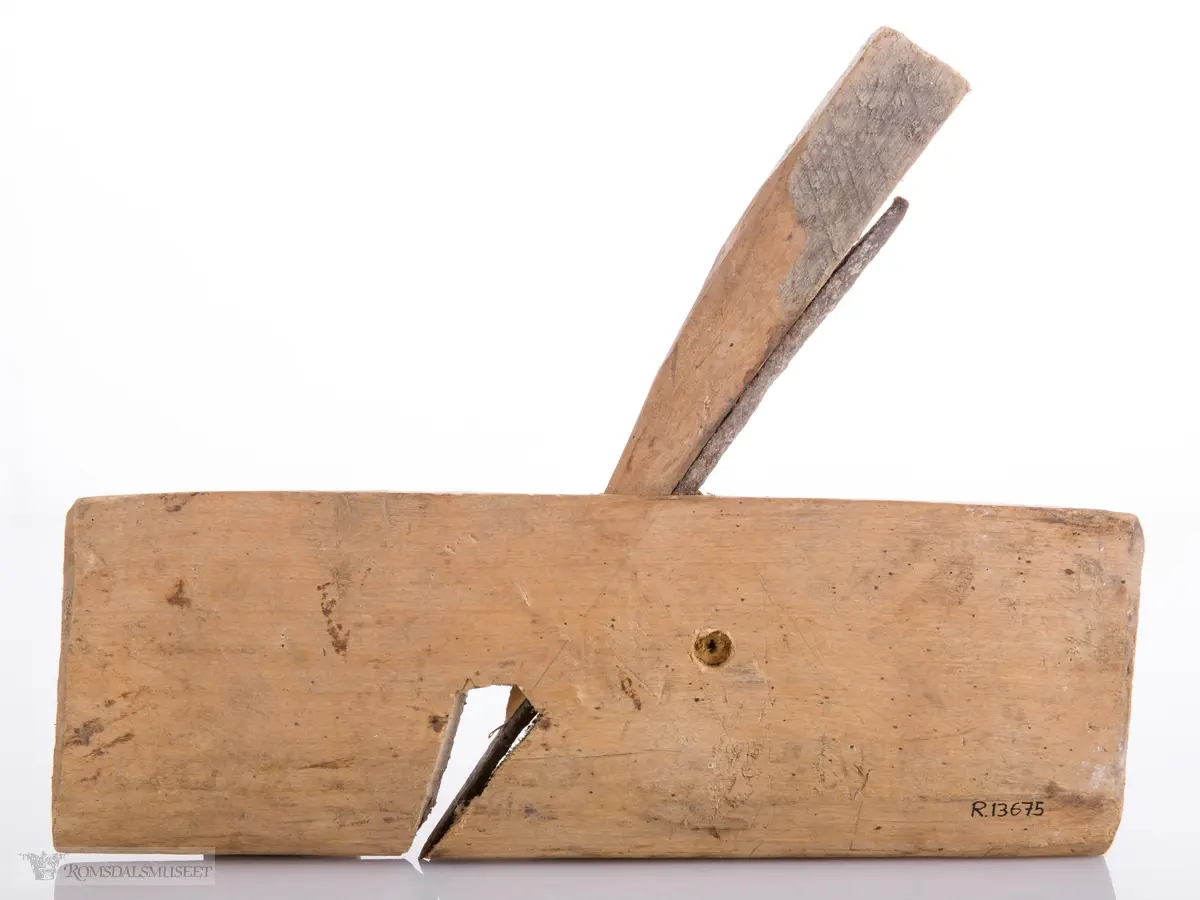 Enkel høvel skåret ut av et stykke tre som er avrundet under. Langt avrundet jern og utskåret kile.