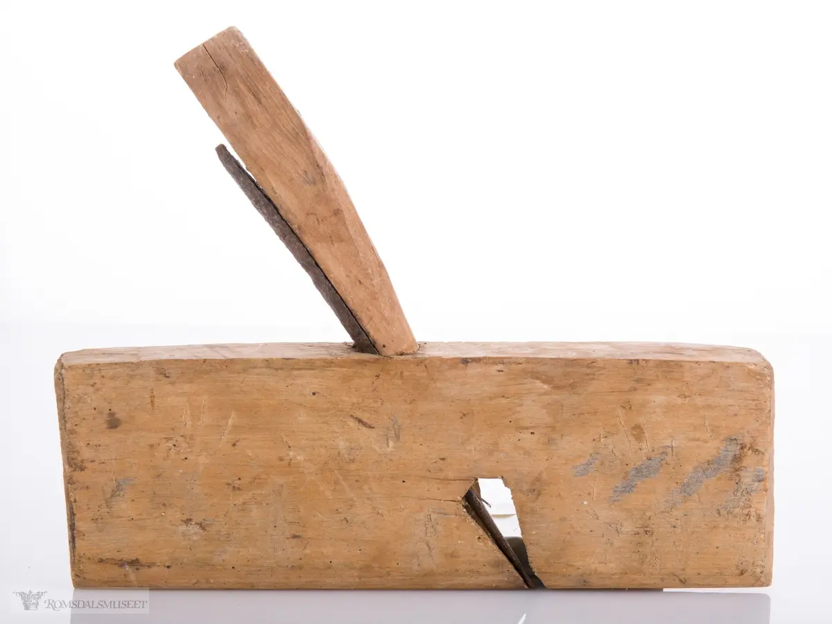 Enkel høvel skåret ut av et stykke tre som er avrundet under. Langt avrundet jern og utskåret kile.