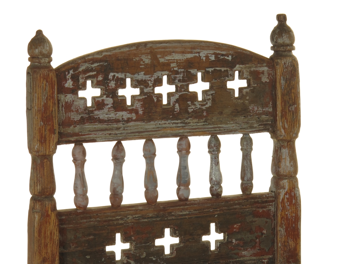 Senmiddelaldersk type, av dreiede pinner. Muligens opprinnelig kirkestol, da der er rader med kors i ryggen. Armlenene har på undersiden festet 6 små  balustre, som nedentil er festet i nok en dreiet tverrligger. Der har likeledes vært balustre (3 stk) under sargen i fronten ned til den øvre tverrstreber. Ryggen består av avvekslende dreiede balustre i tett  rad og horisontale bretter med utskårne gjennombrutte kors. Buet toppstykke. Endene av bakstavene har dreide knotter.