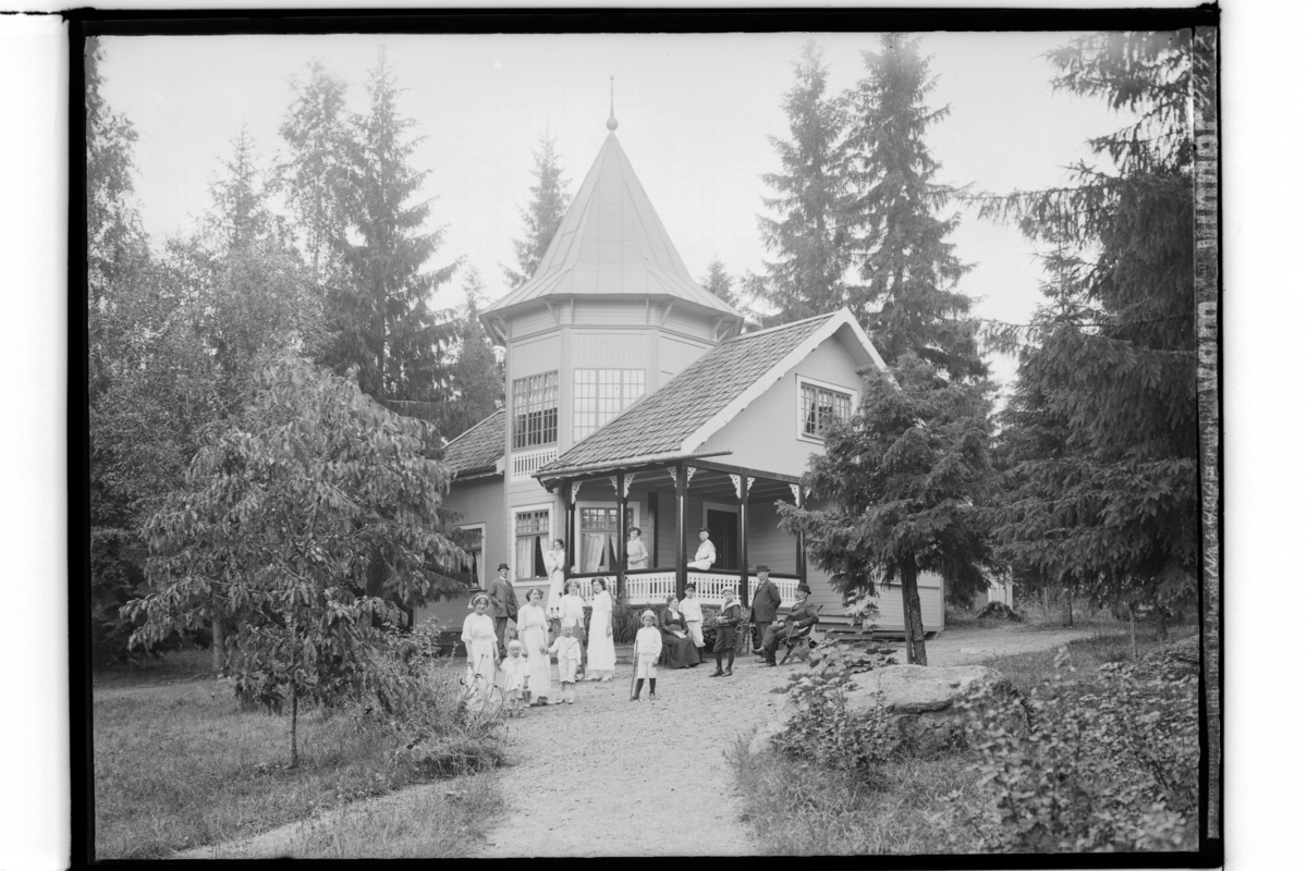 Sekelskiftesvilla med torn, 15 personer framför villan.
Byggmästare P.A. Gillberg