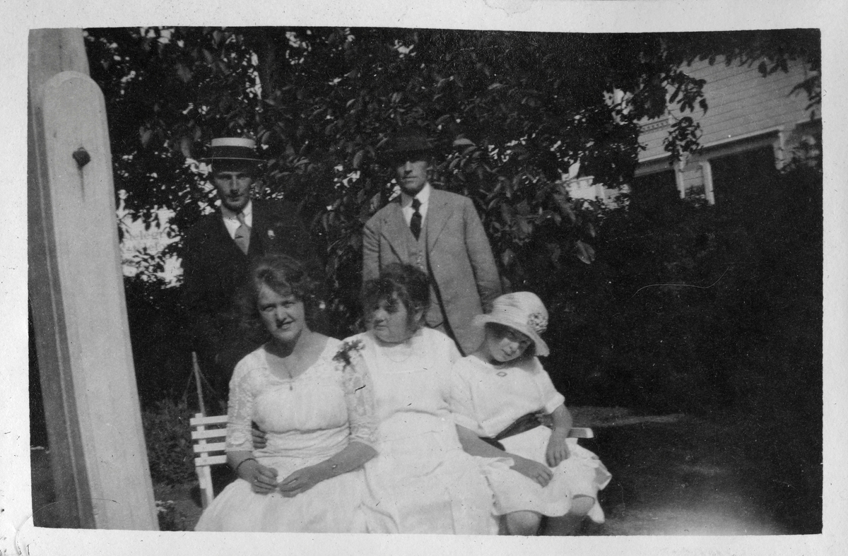 Gruppe mennesker på en benk i hagen ved Grand Hotel, Lillesand 1921. Bildetekst: "Lillesand, 1921"