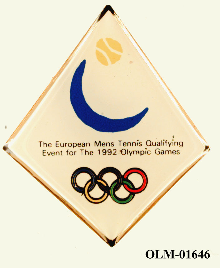 Hvitt firkantet merke med blå sigd og gul tennisball på den øvre delen, tekst over to linjer på midten og de olympiske ringer i farger nederst.