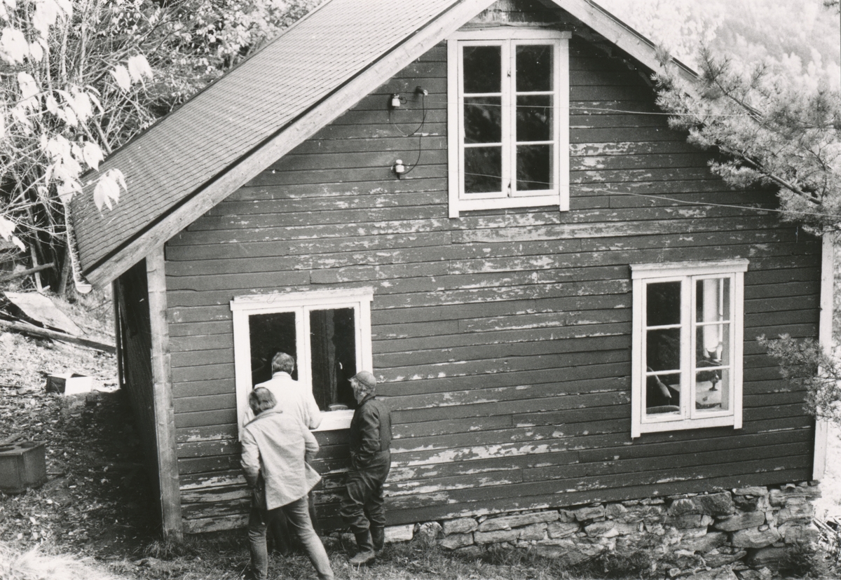 Et stovehus på en husmannsplass, Overå. Tre menn står utenfor og kikker inn vinduet