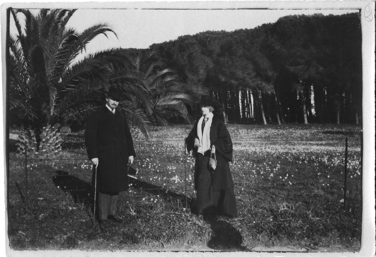 En man med kamera i handen och Ester Bauer står vid en äng utanför Rom i Italien julen 1908.