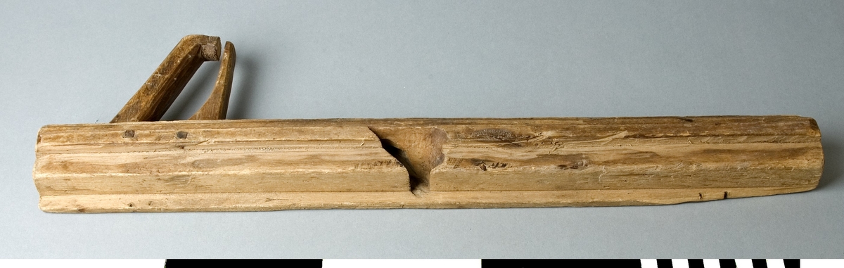 Hyvel av bokträ. En lång falshyvel som har fasta anhåll. Hyveln är avsedd för falsning av bräder. Det fasta anhållet tillåter hyvling till 20 mm djup. Hyveljärn saknas till hyveln. Hyveln har ett slutet handtag i den bakre änden. Handtaget som är fäst i stocken med två genomgående träplugg har ett brott i den övre delen. Hyveln har följande inskuret på den ena långsidan: Årtalet 1852, vilket kan vara tillverkningsåret. Mellan 18 och 52 står D2 ett snedstreck och därunder j4m. Till vänster om årtalet står ett sirligt skuret I eller J. Till höger finns ett bomärke eller signatur i form av två trianglar ställda med spetsar mot varandra med ett streck som tangerar den vänstra övre spetsen.

Funktion: Handhyvel, för putsning av kanter och profiler