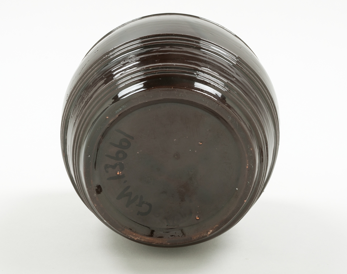 Burk med lock, Bo Fajans, tunnformig, mörkbrun glasyr. Höjd 17,5 cm. 
Prov på fabrikens äldsta tillverkning, 1880-talet.