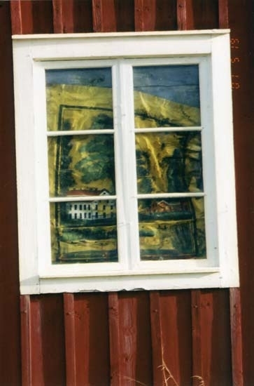 En bemålad rullgardin fotograferad utifrån genom fönsterglaset.