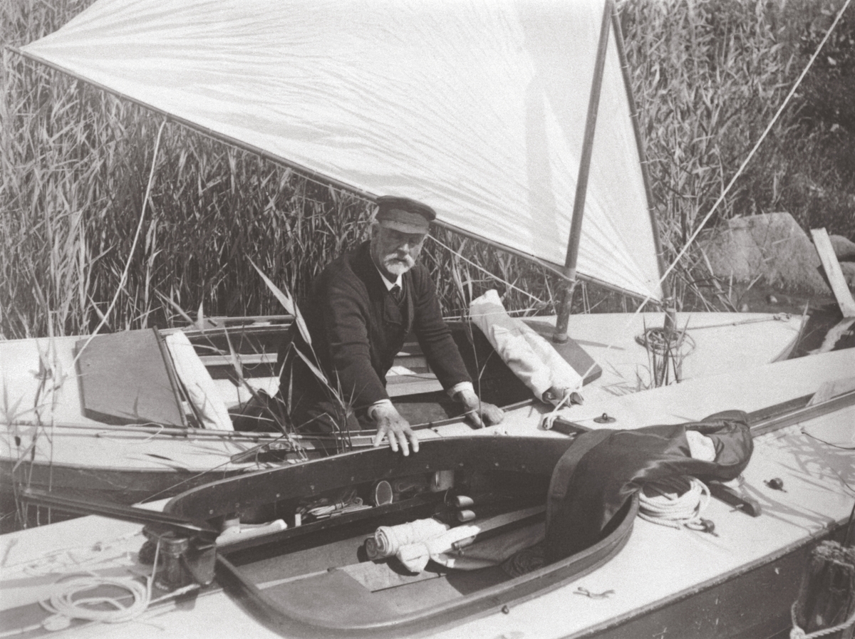 "Kommendör Carl Smith fotograferad av Erik 'Boa' Boström vid ett av sina besök hos gamle kommendören. Närmast Boa:s barlastade 3B-are 'VIKING'. Foto antagligen 1915, då Boa besökte Smith. Kommendörens båt kan vara kanotyachten 'RARA', som ritades för en klass där längd och bredd i vattenlinjen inte fick överstiga 6.50 m. 'RARA' deltog en gång i en kappsegling mot betydligt större båtar, och vann då 1:a priset."(uppgiftslämnare L. Reinholdson)