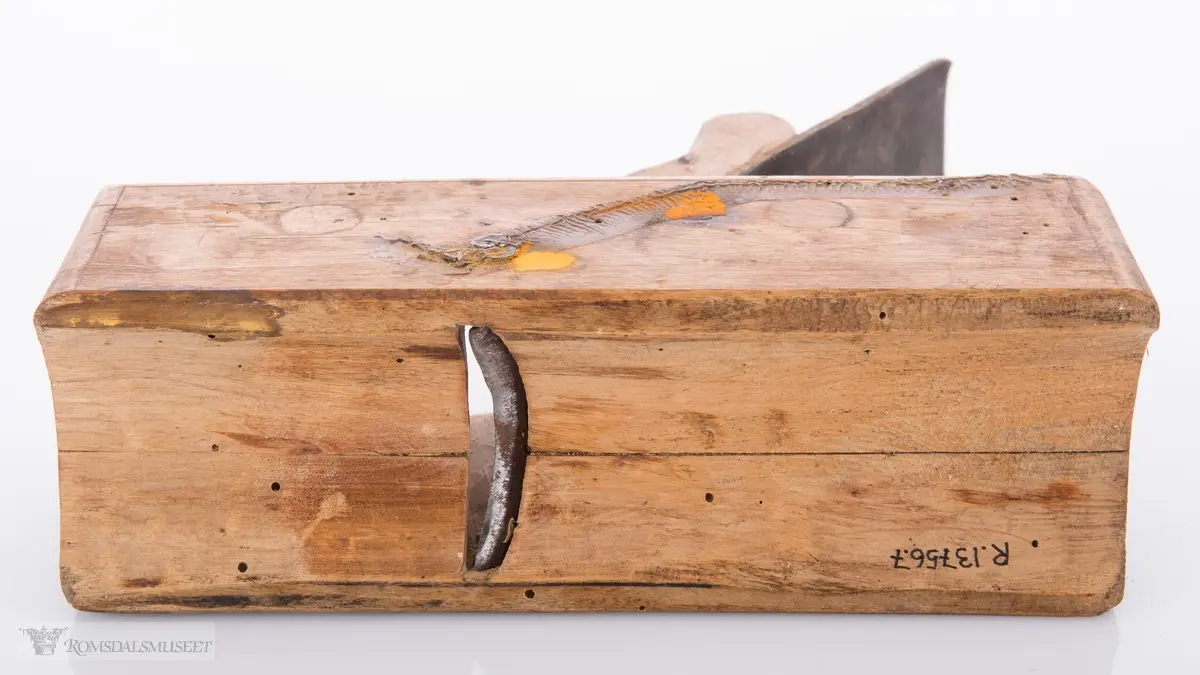 Liten rektangulær høvel med jern og kile. Konkavt u- formet spor i sålen.