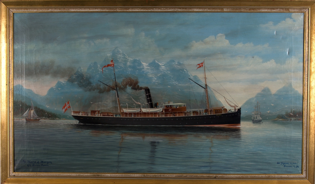 Skipsportrett av DS HERA i fjordlandskap med høye, spisse fjell i bakgrunnen, antagelig nordnorsk landskap. Har BDS vimpel i framre mast og postflagg i akter. I bakgrunnen en jekt og en bark.