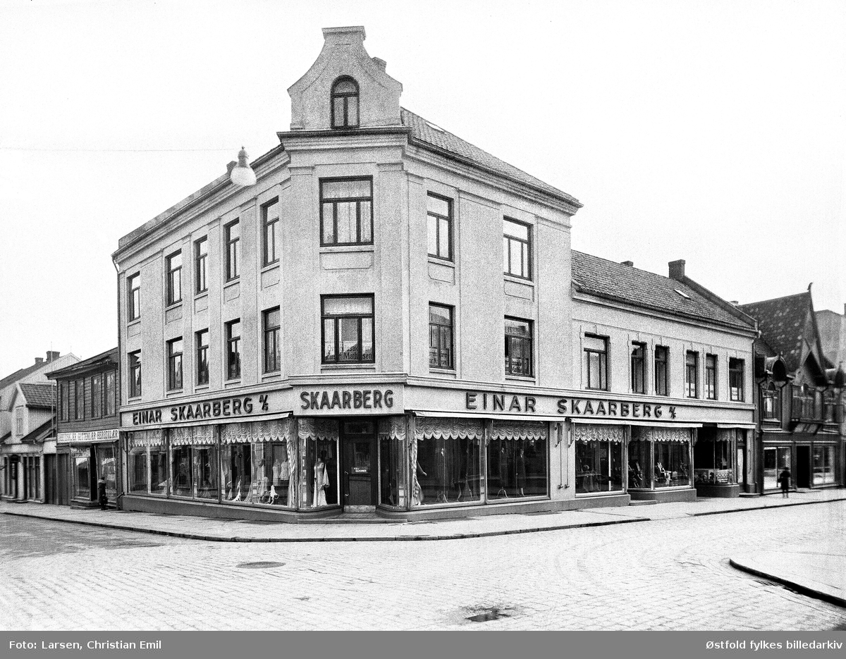 Forretningsgårder i Sarpsborg, St. Mariegate 105.
Einar Skaarberg A/S, manufakturforretning. Skilt "Overretssakfører Mathisen" i 2. etasje.
Til høyre for Skaarberg ser vi btikken til pølsemaker Arnt Bergby, i St. Mariegate 103.
