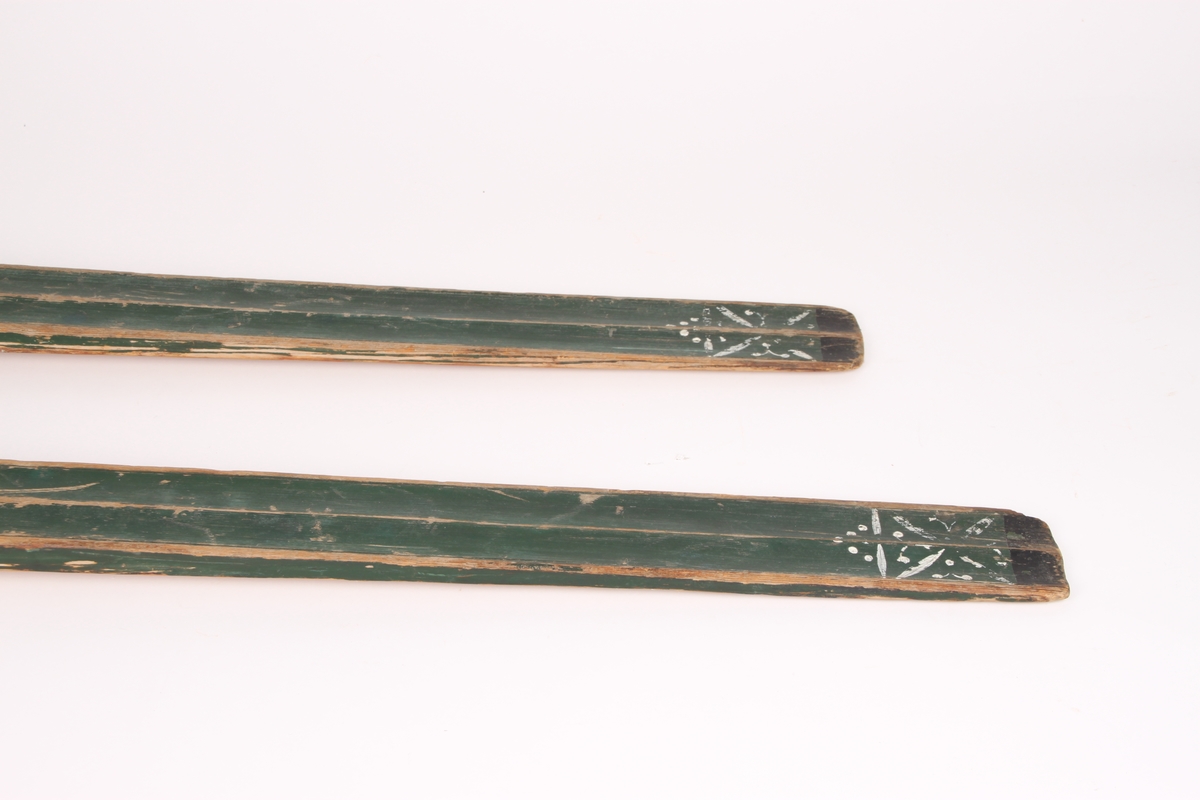 Et par treski i helved med lang og smal tupp, flat overside og fortykning under. Avsmalnende framski og jevnbred bakski og møneformet rygg langs hele skiens lengde. Dekoren er fra Krødsherad med fremre del av framskien malt i svart, og med rosett og navn med årstall i hvitt. Rosett også på skienes bakende. Skiene har tåstropp av vidje og har sannsynligvis hatt ilkebinding. Bindingshullene har innskjæring med skråsnitt på skienes sider. Skiene er rett avskåret bak. Ingen rand under.