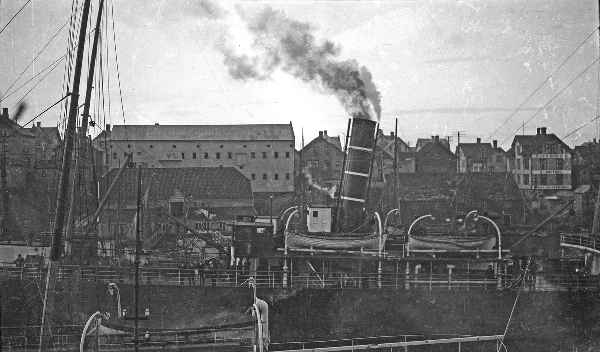 Havnbilde. Dampskip på vei gjennom sundet. Bebyggelsen på Risøy i bakgrunnen. Hverdagsfoto.