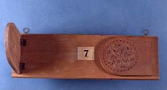 Text i liggaren ang inv nr 81740:1-11: "Modellserie i svarvning och träsnideri i Skara slöjdskola 1870-1890 av Alb. Larsson, uppfästad å större träskiva med nummer".
Modell nr 7, bokställ, upphängd med två metallöglor, ärgade. Två uppfällbara sidor av päronträ prydda med karvsnitt. Basen är av asp. Sidorna är fastskruvade vid basen med två gångjärn av järn vid vardera sidan.


Neg.nr: 1984-0001
Sakord: MODELL
Tillverkningstid: 1860-1870
Material: asp? päron? järn
Teknik: figursågat karvsnitt skruvat
Mått: L=251 B=95 H=17
Vikt: