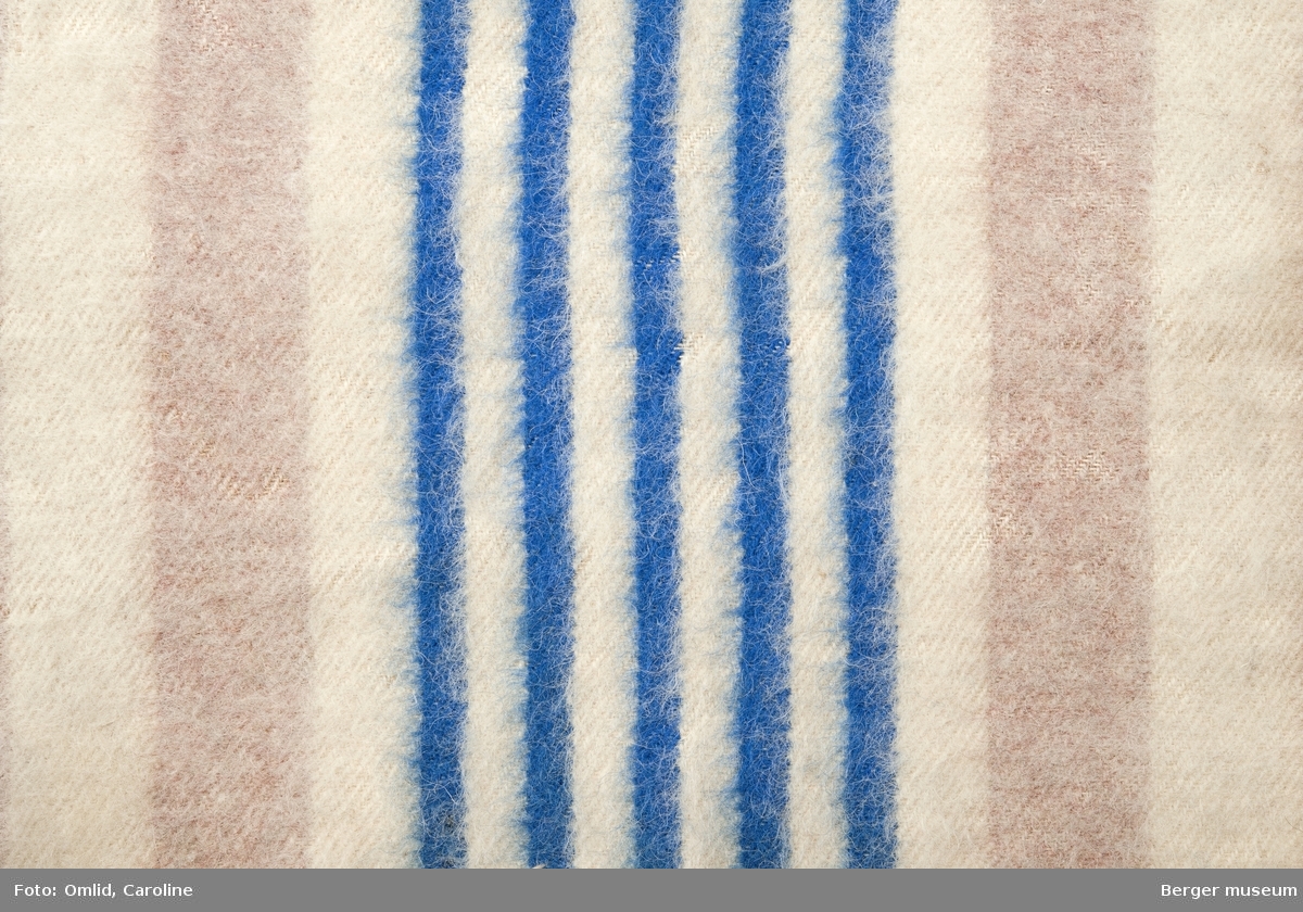 En prøve. Teppe i stripemønster; rosa og hvite striper.  Mønsterbord i smalere striper, fem blå og fire off-white.