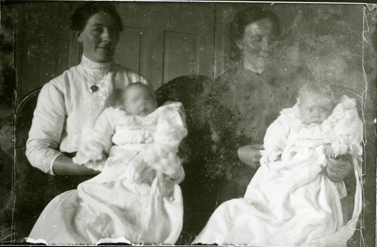 To kvinner sit med kvart sitt barn på fanget.