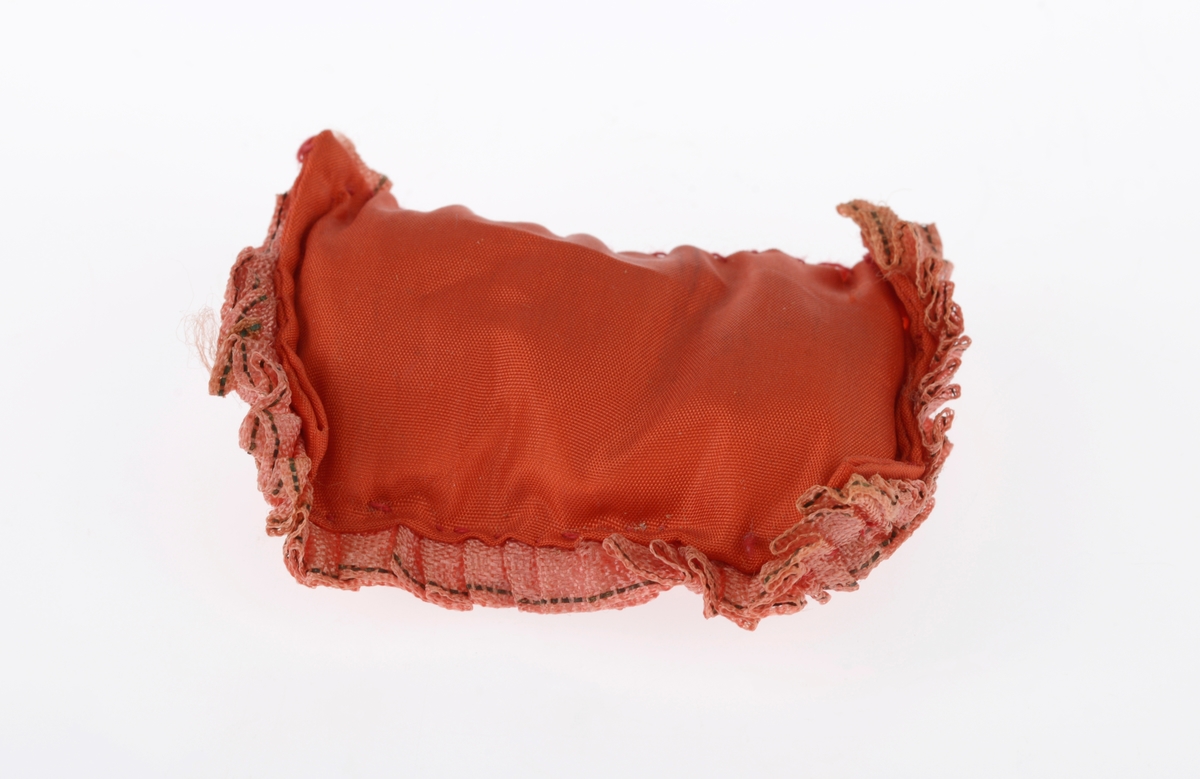 En liten komse med en pute og et dukkehode i. Gjenstandene er undernummerert 01-03. 
FTT.54491.01: En liten komse laget av et uthulet stykke tre som er kledd med garvet reinskinn. På kalesjen er det dekorert med røde pyntebånd av ull festet på et gult bånd av ull. Det er også to flerfargede dusker på kalesjen. i kalesjen er det festet et tvunnet ullbånd som er festet i den andre enden av komsen slik at man kan bære den. Det er også sydd på et pyntebånd i gult og rødt på oversiden.
FTT.54491.02: En liten rød pute sydd av silkestoff som ligger inni komsen.
FTT.54491.03: Et dukkehode laget av plast som ligger i komsen. Håret er støpt og er krøllete. I ansiktet er det malt på øyne og munn. Rundt halsen har dukken et silkebånd.