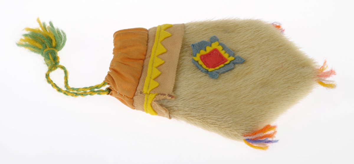 En liten veske laget av garvet reinskinn. Den er spiss i enden og har en slags ruter-form. Øverst er det sydd på en dobbel kant av oransje bomullsstoff. Gjennom denne er det tredd en tvunnet ullsnor i gult og grønt med en dusk i enden. Med snoren kan man åpne/lukke vesken. Deretter er det sydd på en stripe med lys oransje ullstoff der det er sydd på en trekantbord av gult ullstoff. På midten av vesken er det sydd på tre firkanter av filt oppå hverandre. Den nederste er blå med takkete kant, deretter er det en gul med takkete kant og til slutt er det en rød firkant. I spissene nederst på vesken er det sydd på små dusker av ullgarn i rødt, blått, hvitt og gult.