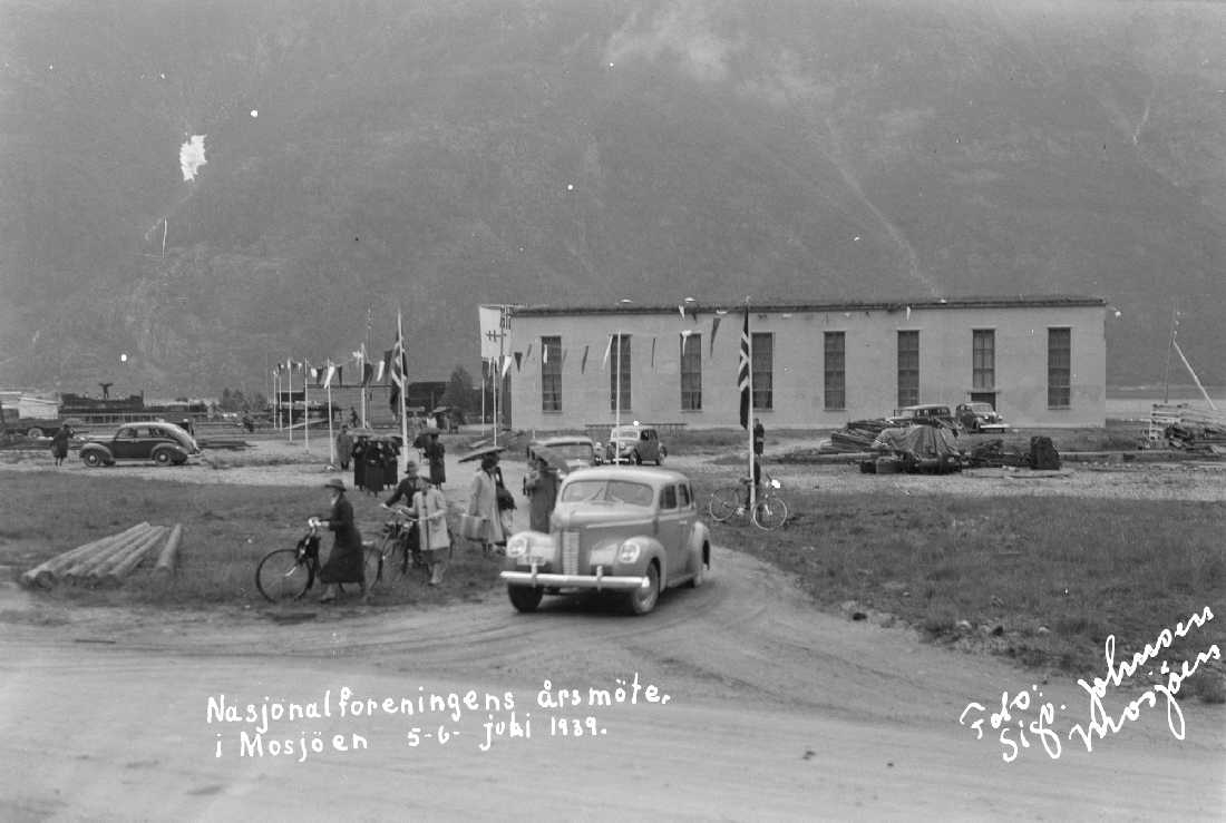 Nasjonalforeningens årsmøte i Mosjøen 5-6 Juli 1939. 
Møtet har blitt avholdt i lokstallen på jernbanen.Pyntet med flagg. Folk og biler på tur ut fra møtet.
