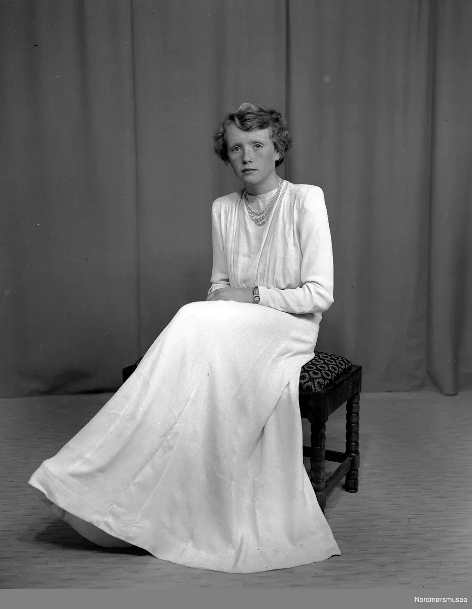Foto av en ukjent ung kvinne, trolig fra Tingvoll kommune i Møre og Romsdal. Muligens et konfirmasjonsfoto. Datering er sannsynligvis mellom 1950-1960. Fra Nordmøre museums fotosamlinger, Halås-arkivet.
