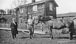 Mann og kvinne, hest, foran bolighus