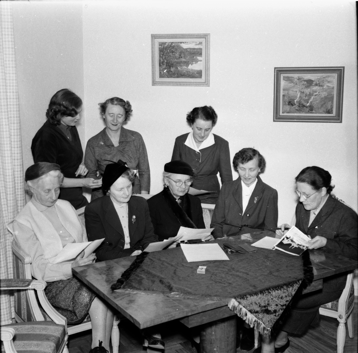 Damer kring ett bord.
Till vänster Fru (Oscar) Björkman, sittande längst till höger Fru Lisa Jonsson Fjäle, Stående Gunnel Jonäng och längst till höger fru (boktryckare) Carlsson.