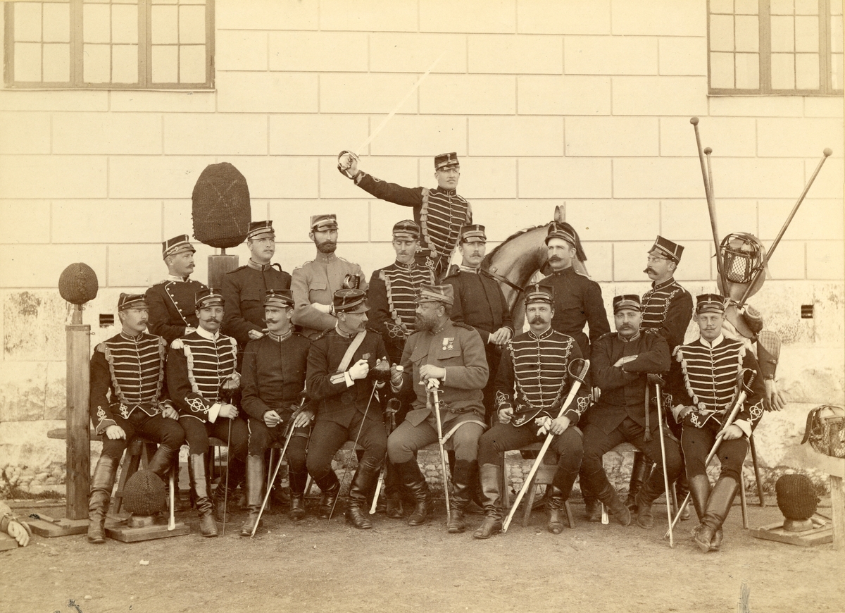 Officerssällskap bestående av husarer, dragoner, infanterister och artillerister poserar framför K2:s förläggning på Ladugårdsgärde under sabelfäktningskurs 1890.