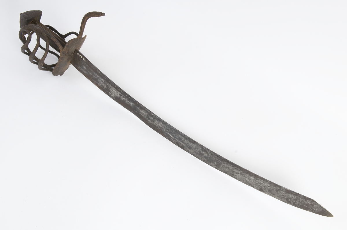 Pyramideformet  knapp med punslet strekdekor. Tregrep. Runde parerstenger med filt strekdekor og svakt nedbøyd bakre parestang. Fremre parerstang er brukket. Kurvfeste med runde bøyler med utsmidde, skråfilte midtpartier. Nyreformet parerplate med tombøyle på innsiden. 
2 sidebøyler på innsiden.
Enegget, kileformet krum klinge med  ryggstilt blodrand. Gjeddenebb.  
Klingens innside merket med ett smedstempel.