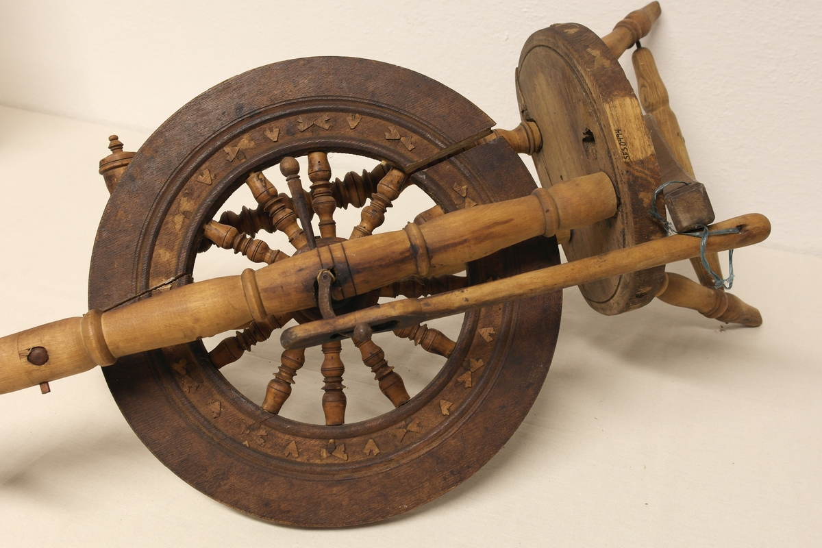 Stående hjulrokk i tre med spinneapparatet plassert over hjulet. Rokken har opprinnelig hatt tre bein.