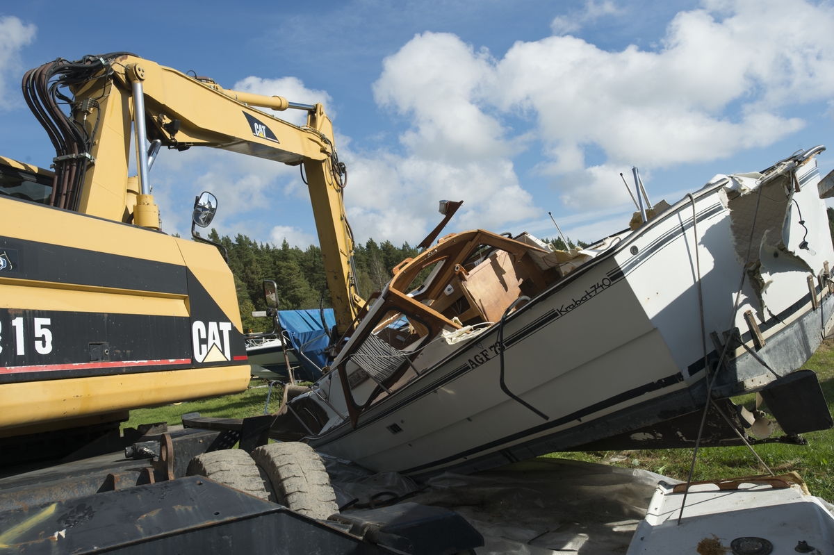 Företaget Båtskroten demonterar och skrotar en äldre plastbåt.
