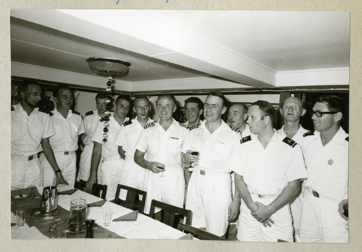 Bilden föreställer sommaruniformsklädda män som har mottagning i minfartyget Älvsnabbens mäss under långresan 1966-1967. Troligen är det gunrummet som här har fungerat som mäss.