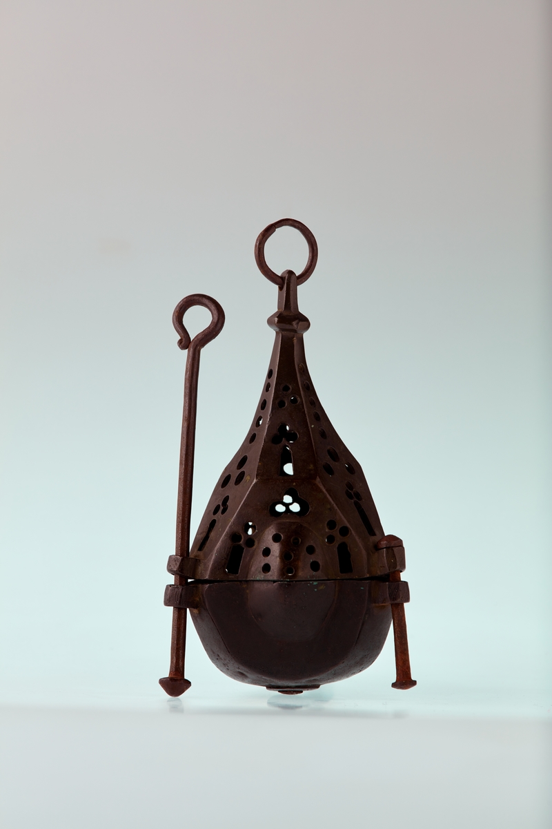 Bronse. 6 sidet. 3 av sidene med kuleformet utvidelse. Skål med pipe i centrum. Firpassformen viser hen på slutten av middelalderen. Den skjematiske og grove utførelse tyder på hjemlig produksjon. Ligger nær å gjette på Tunsberg. Etter reformasjonen er en lysepipe satt inn. Mulig denne lysestake har hengt etter en snor og likeledes den lange glidestangen