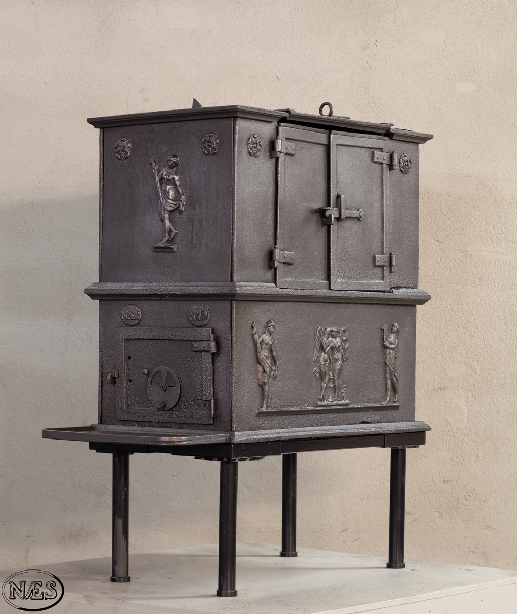 Kokeovn i to etasjer med eget fyrkammer og kokerom. Kokerommet kan åpnes med to dører på langsiden og med en luke i topplaten. Ovnsdøren til fyrkammeret er på kortsiden 1 etg. På langsidene i 1. etg er det tre muser og en engel med lette draperier på en enkel profillist. På kortsidene 2. etg er det draperikledd dansende muse på enkel profillist med en rosett i hvert øvre hjørne. Langsidene i 2.etg er dekorert med en rosett i hvert øvre hjørne.